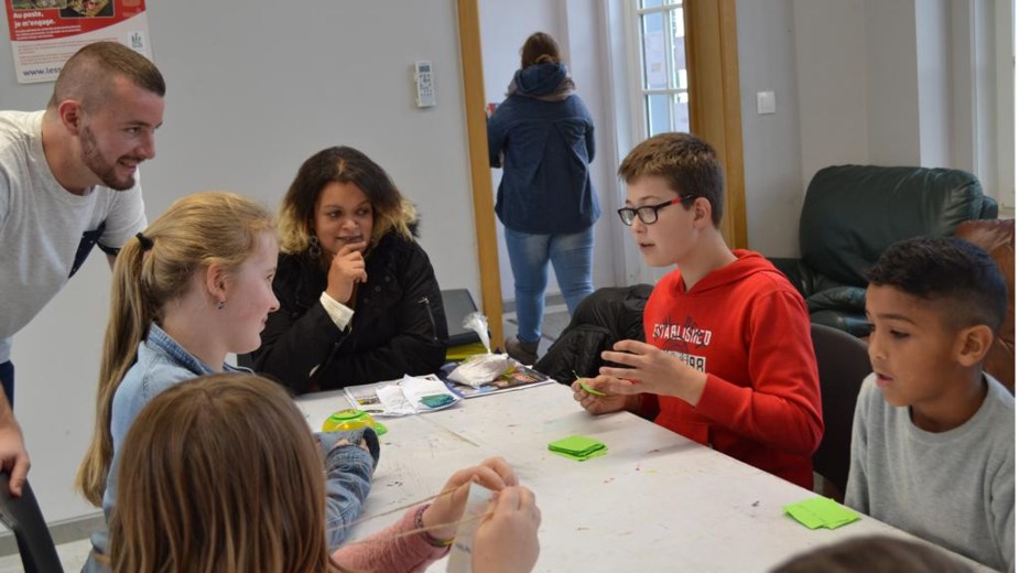 Groupe d’enfants et adultes participant à une activité collective autour d’une table.