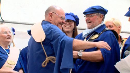 Personnes en tenue traditionnelle bleue se saluant lors d’un événement festif.