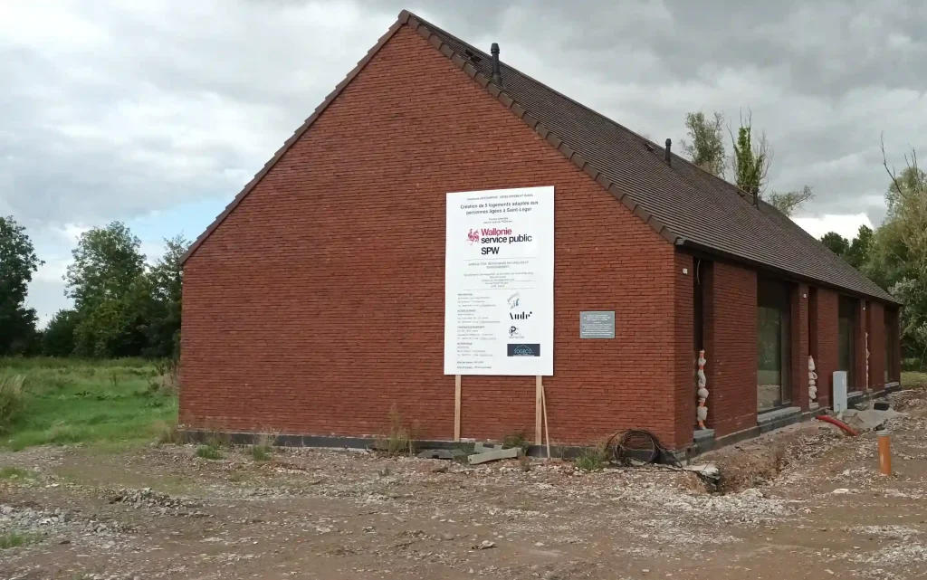 Bâtiment en briques en construction avec panneau de projet de logements publics.