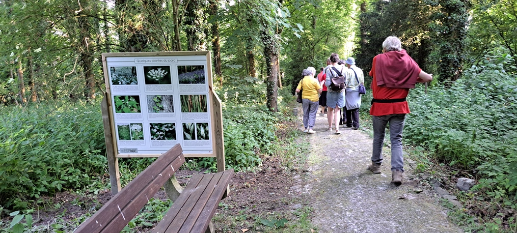 Photo d'un sentier avec panneau didactique et personnes qui marchent
