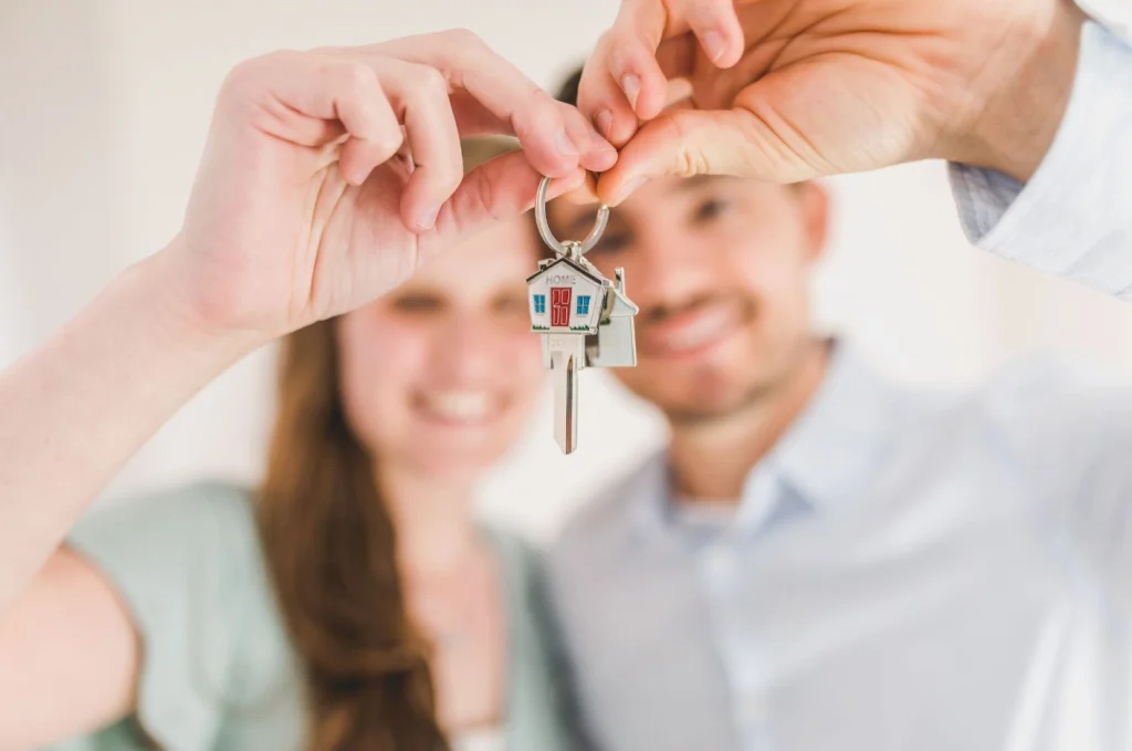 deux jeunes adultes avec une clé et un porte clé en forme de maison