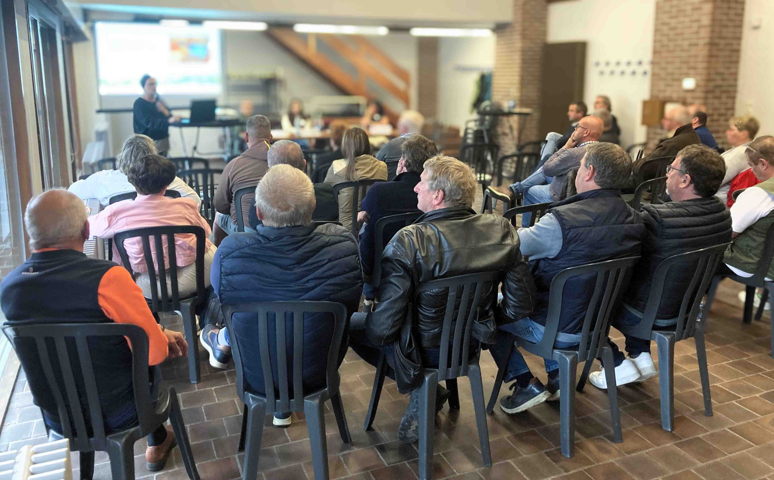 Lors d'une réunion de CLDR dans une salle, une trentaine de personnes assises sur des chaises au premier plan qui assistent à une présentation