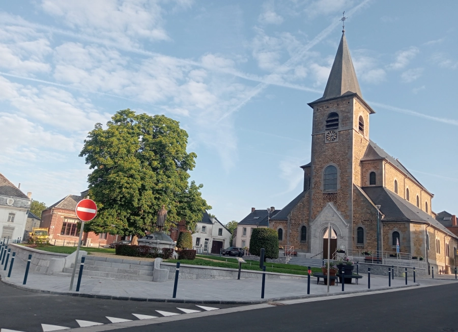 Nouveau centre de Sivry inauguré le 20 juillet 2025, avec la place aménagée, statue centrale et église en arrière-plan sous un ciel partiellement nuageux.