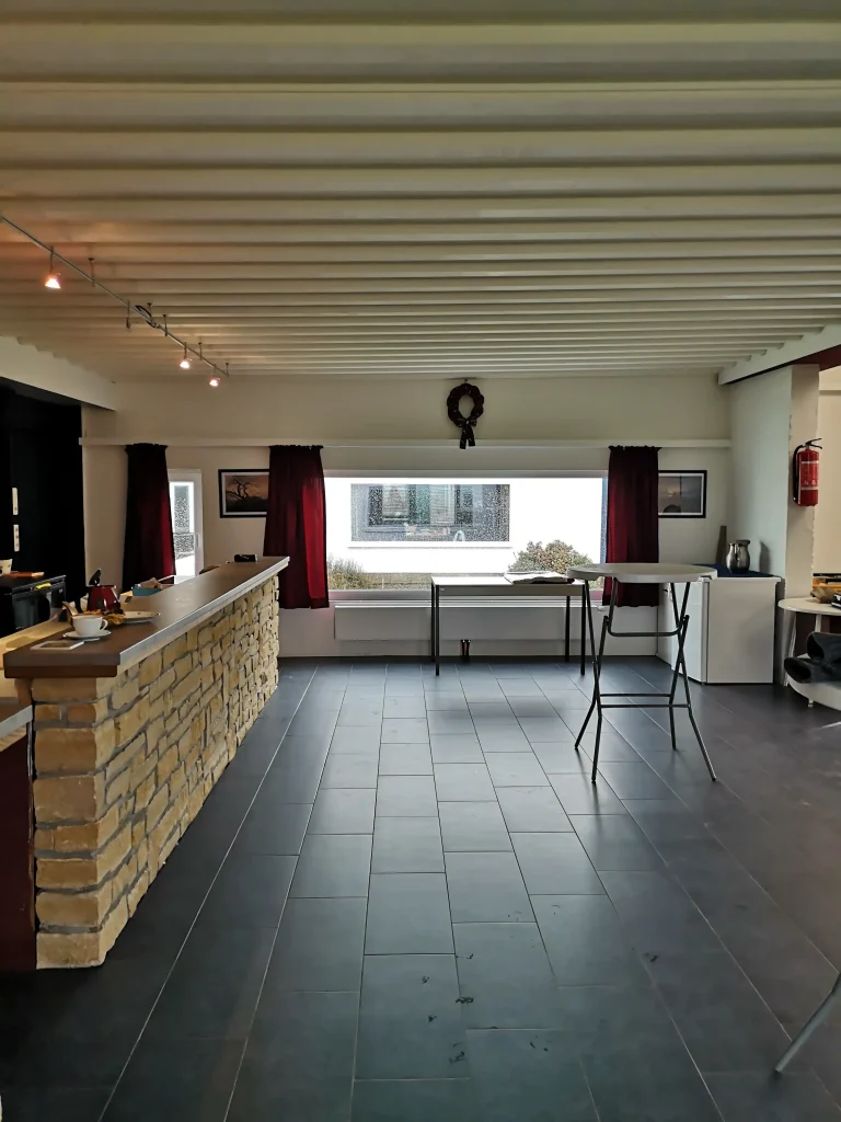 Intérieur de la salle qui deviendra la maison de village de Poncelle. On y voit sur la gauche un bar en pierre, au fond une baie vitrée et sur la droite, un espace salle vide.