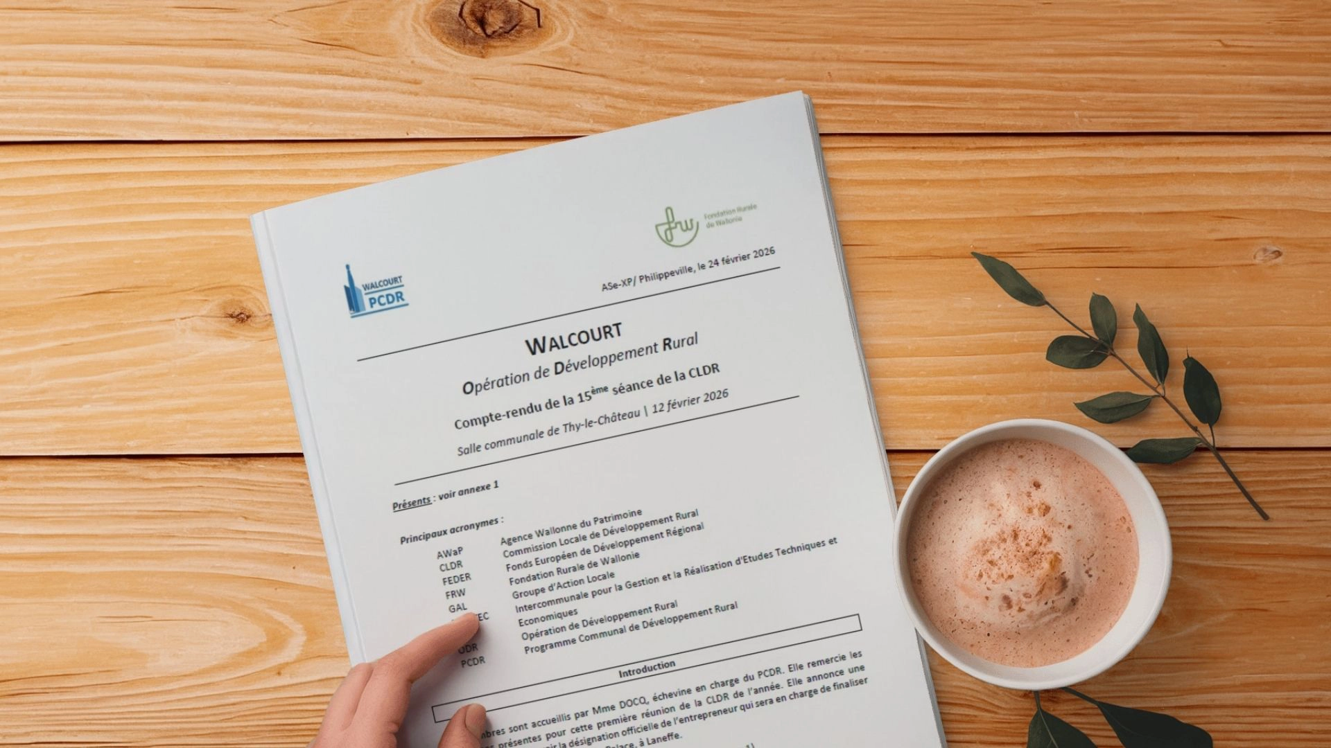 Page de garde du compte rendu de la CLDR de Walcourt du 12 février 2026, posée sur une table en bois, avec une tasse de café à côté.