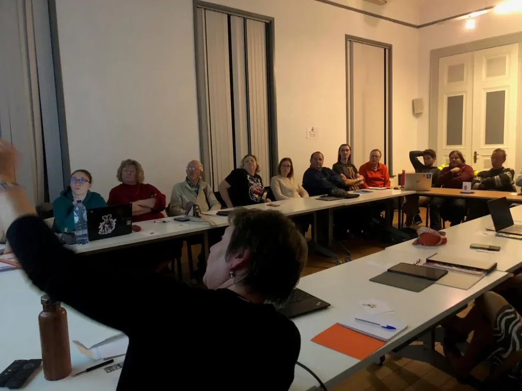 Plusieurs personnes installées autour d'une table et regardant une présentation